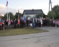 Pamiątkowe zdjęcie osób zgromadzony przed pomnikiem