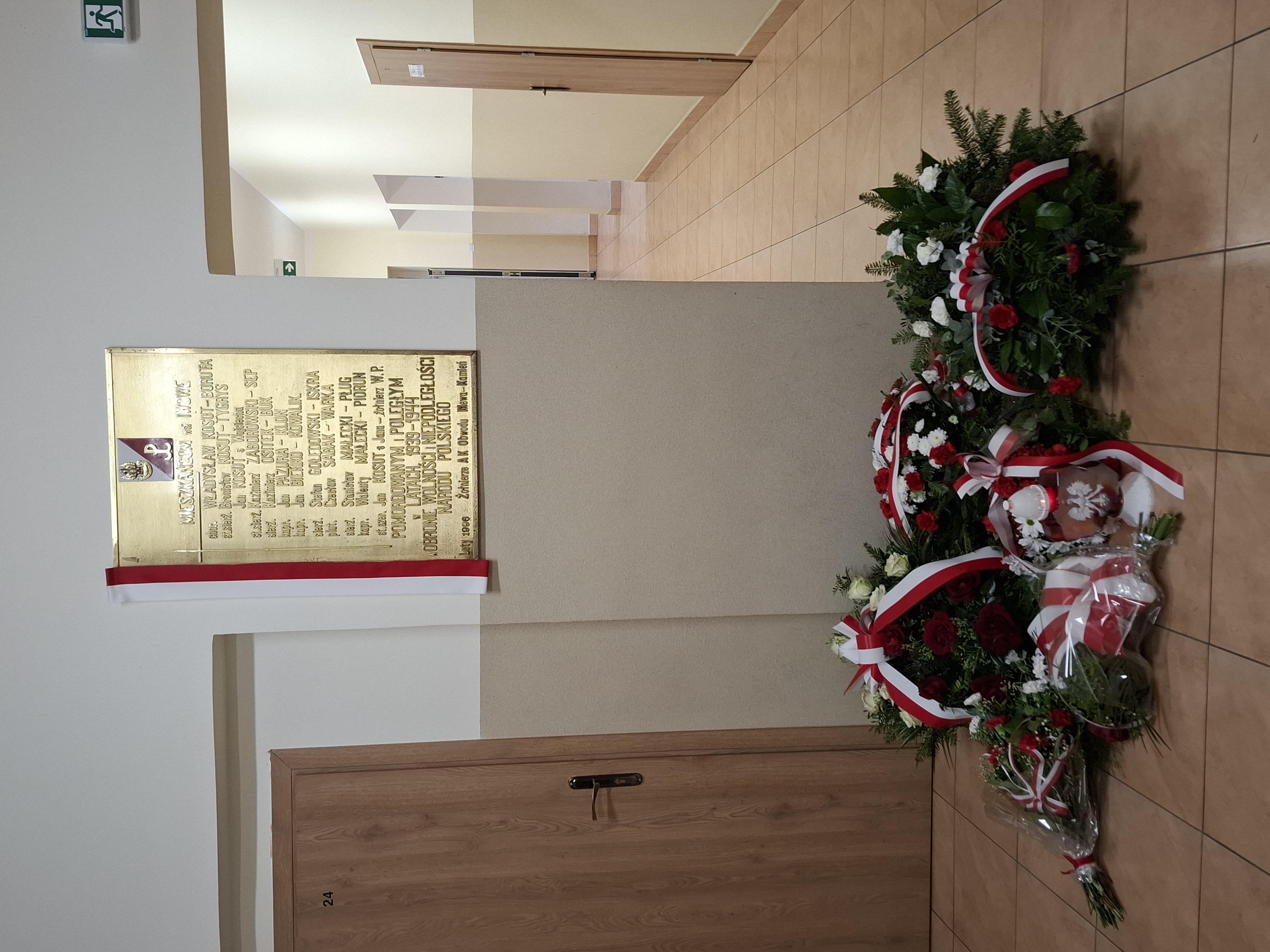 Tablica epitafijna oraz złożone pod nią kwiaty